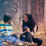 two women sitting on ground near bonfire