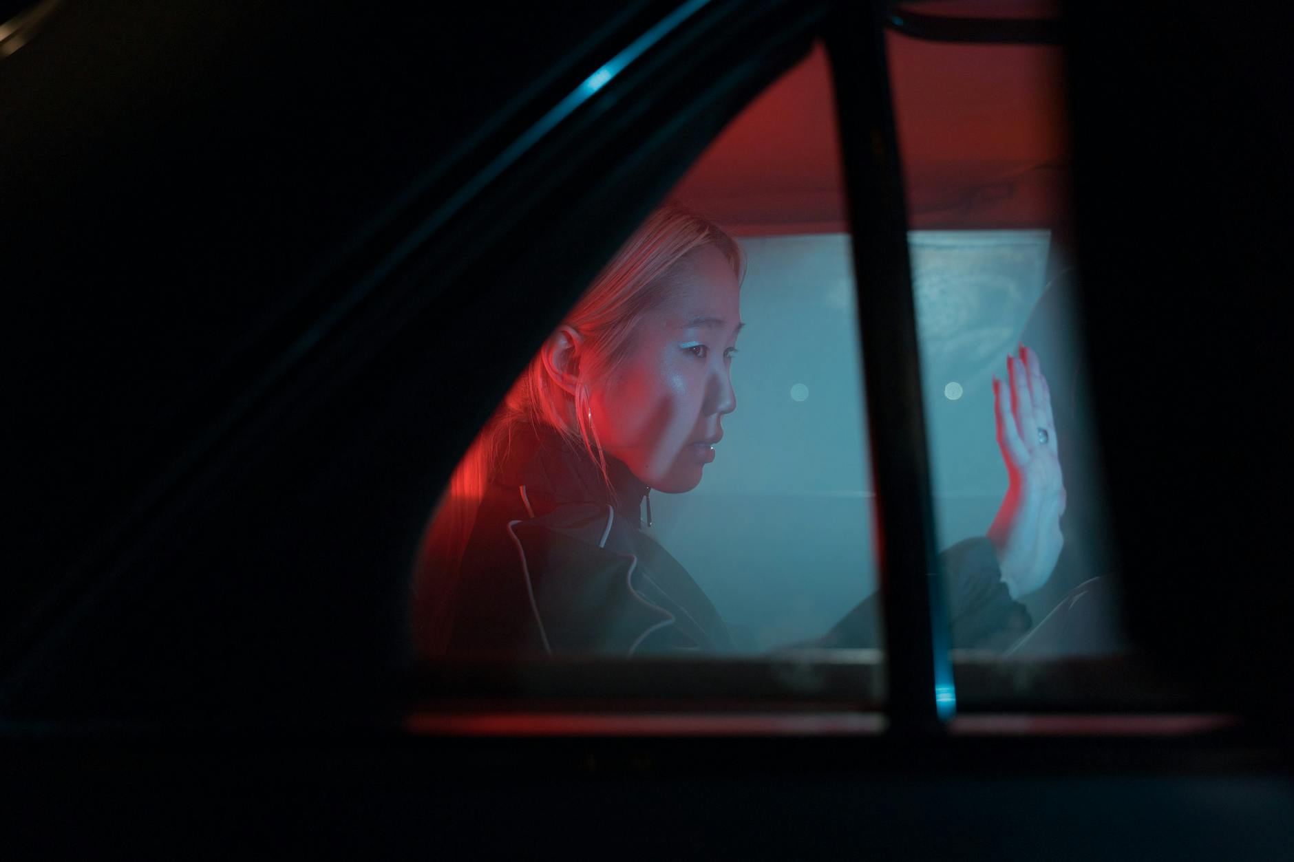 woman inside a car waving goodbye