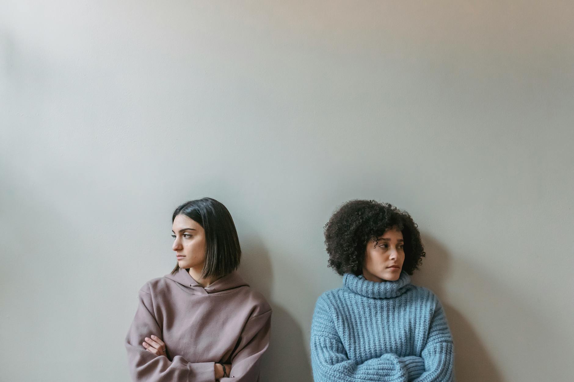 upset diverse women near wall