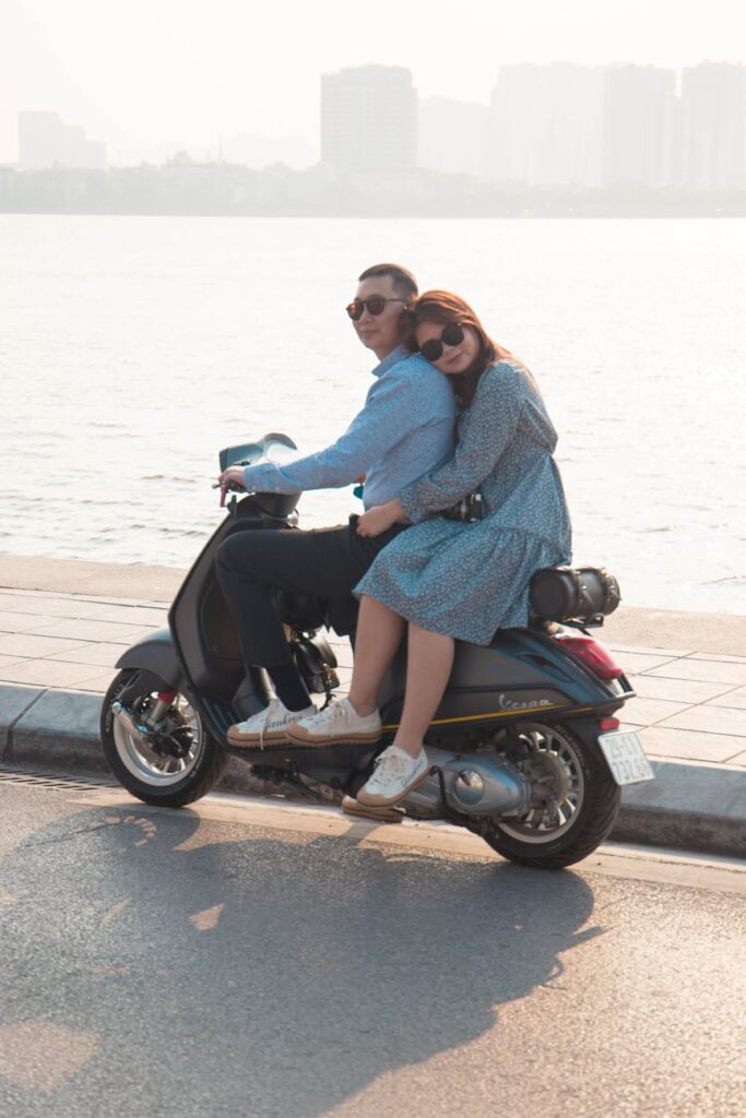 young couple riding a motorcycle along the sea coast